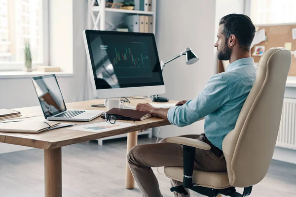 オフィスに座っている間にコンピュータを使用してデータを分析する若い現代のビジネスマン — ストック写真