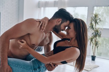 Güzel genç çift kucaklayan ve yatak odasında yüz yüze dururken gülümseyen