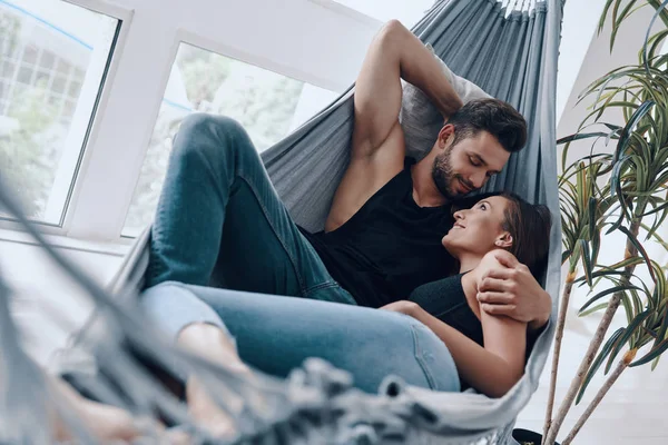 Beautiful Young Couple Embracing Smiling While Resting Hammock Indoors — Stock Photo, Image