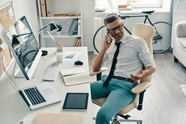Σίγουρος Επιχειρηματίας Που Μιλάει Στο Τηλέφωνο Ενώ Κάθεται Στο Γραφείο — Φωτογραφία Αρχείου