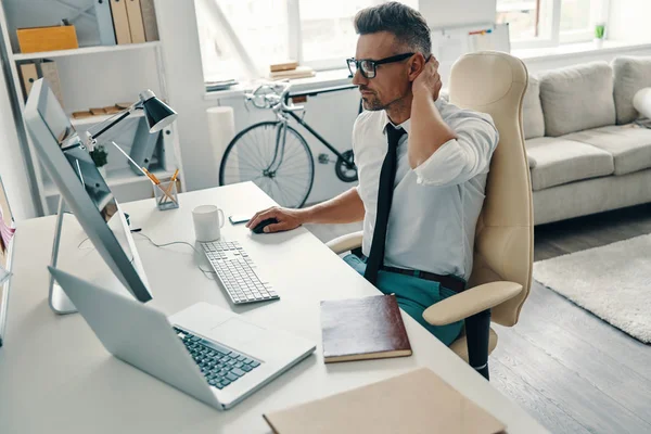 オフィスに座っている間 コンピュータを使用して働くシャツとネクタイの思慮深い若者 — ストック写真