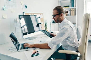 Ofiste otururken dijital tablet kullanarak gömlek iyi görünümlü genç adam         