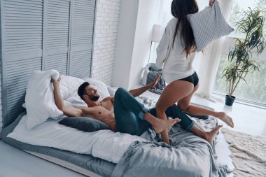 Yatak odasında kaygısız zaman geçirirken eğlenceli bir yastık mücadele mutlu genç çift üst görünümü 
