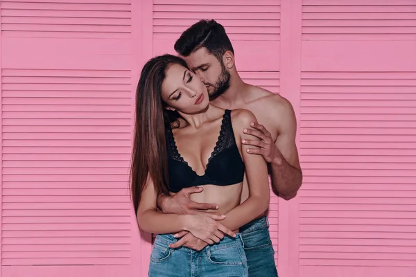 Bonito Jovem Casal Abraçando Enquanto Contra Fundo Rosa — Fotografia de Stock