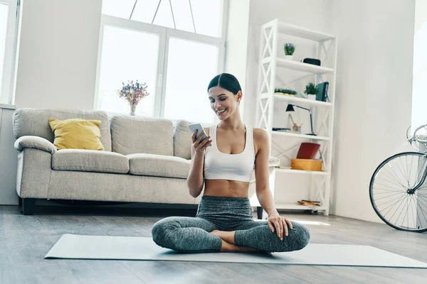 Beautiful Young Woman Sports Clothing Using Smart Phone Smiling While — Stock Photo, Image