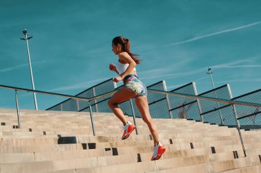 Açık havada egzersiz yaparken çalışan spor giyim güzel genç kadın tam uzunlukta