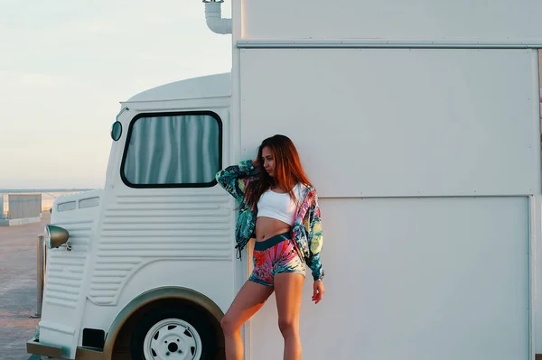 有吸引力的年轻女子在运动服装摆姿势 而站在户外食品卡车 — 图库照片