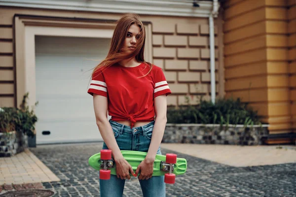 Красивая Молодая Женщина Смотрит Камеру Носит Скейтборд Стоя Улице — стоковое фото