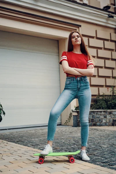 Full length of attractive young woman keeping arms crossed while standing outdoors