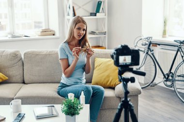 Evde sosyal medya video yaparken saçlarını ipuçları gösteren güzel genç kadın   