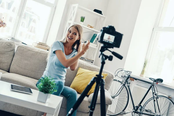 自宅でソーシャルメディアビデオを作りながら 美しい若い女性が笑顔で髪に美容製品を適用 — ストック写真