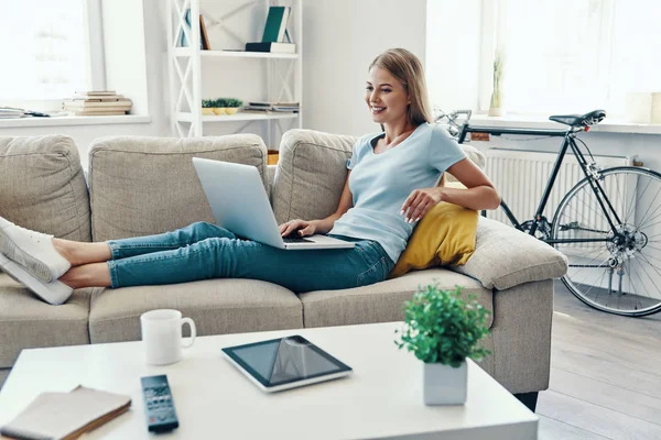 Mulher Bonita Sorrindo Usando Laptop Enquanto Descansa Sofá Casa — Fotografia de Stock