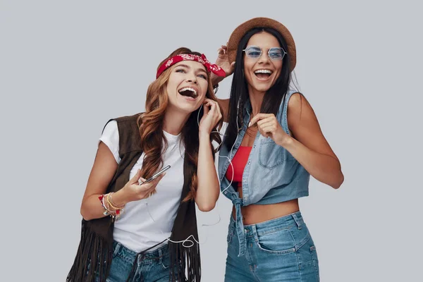 Twee Aantrekkelijke Stijlvolle Jonge Vrouwen Lachen Terwijl Tegen Grijze Achtergrond — Stockfoto