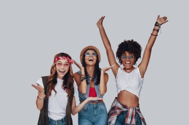 Gri arka planda dururken tezahürat ve gülümseyen üç çekici genç kadın