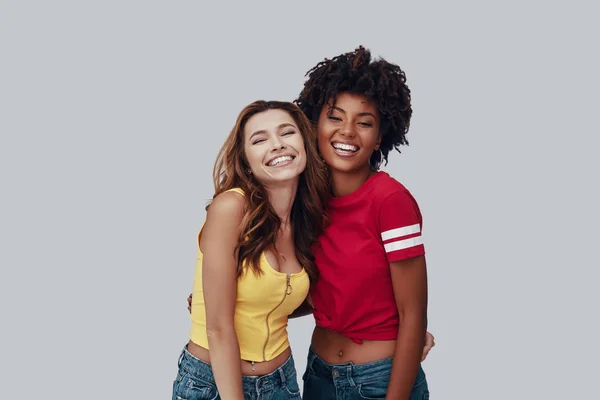 两个有吸引力的年轻女子看着相机 面带微笑 站在灰色的背景 — 图库照片