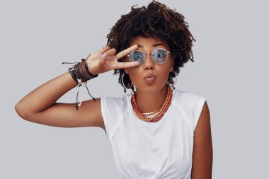 Çekici genç Afrikalı kadın kameraya bakıyor ve yüzünde parmakları ile gesturing