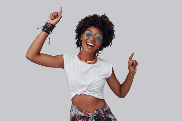 魅力的な若いアフリカ女性カメラ目線と灰色の背景に対して立っている笑顔 — ストック写真