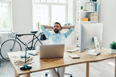 Ofiste otururken akıllı Casual giyim kafası arkasında ellerini tutarak rahat orta yaş adam