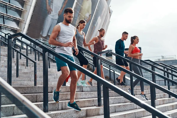 一群运动人士在城市楼梯上慢跑 在奥林匹克体育场的背景 — 图库照片