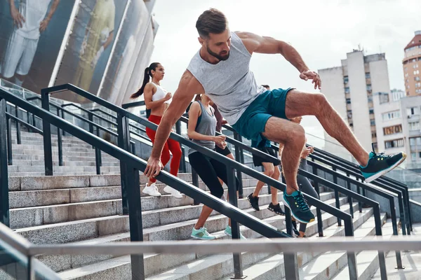 Jovem Roupas Esportivas Pulando Corrimãos Enquanto Exercita Com Seus Amigos — Fotografia de Stock