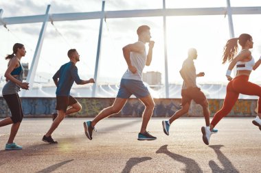 Olimpiyat stadyumu binasının tepesinde şehirde koşu spor giyim gençlerin grubu 