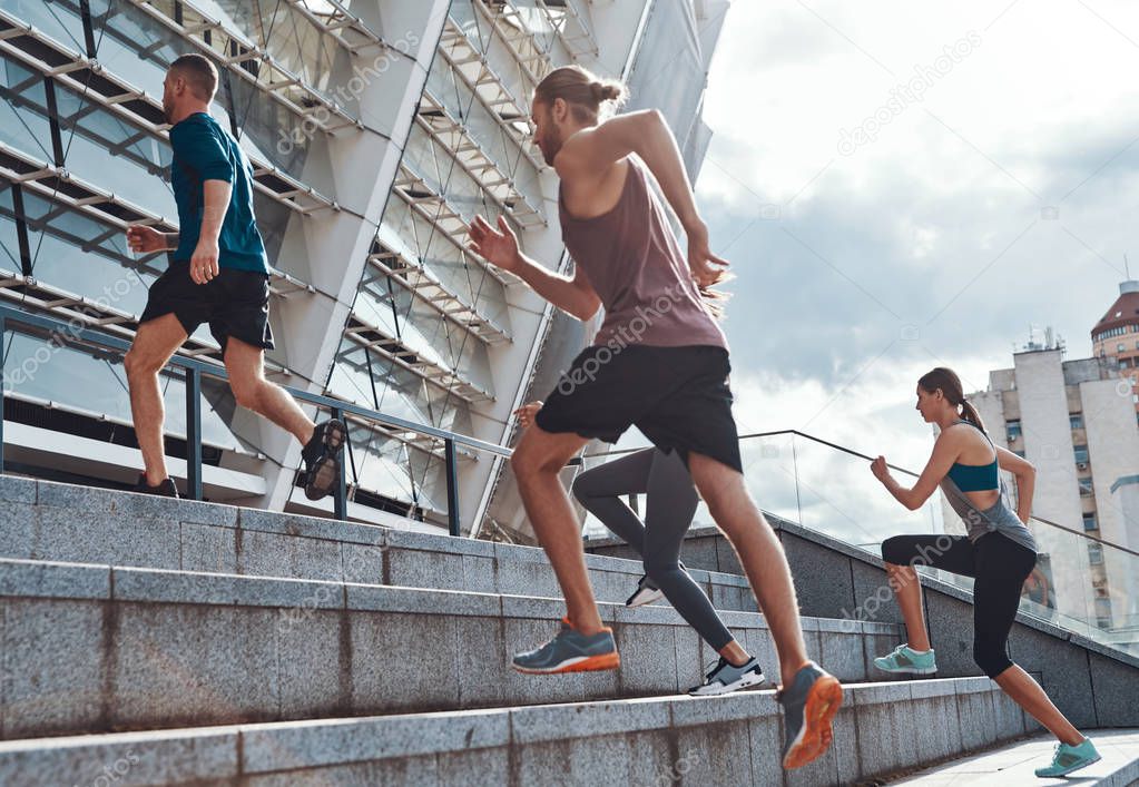 Group of young people in sports clothing jogging on stairs up in city at Olympic stadium in Kyiv 
