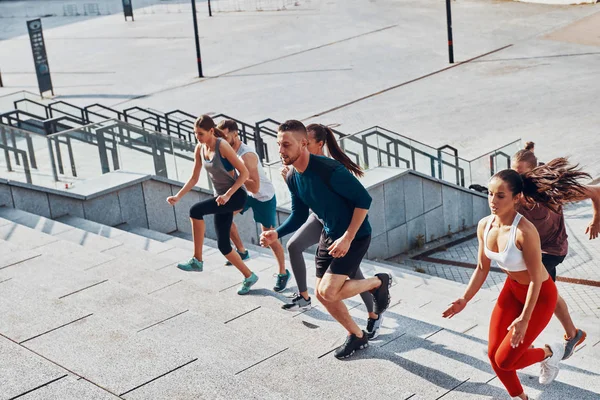 Grupo Jóvenes Ropa Deportiva Trotando Escaleras Hormigón Ciudad — Foto de Stock