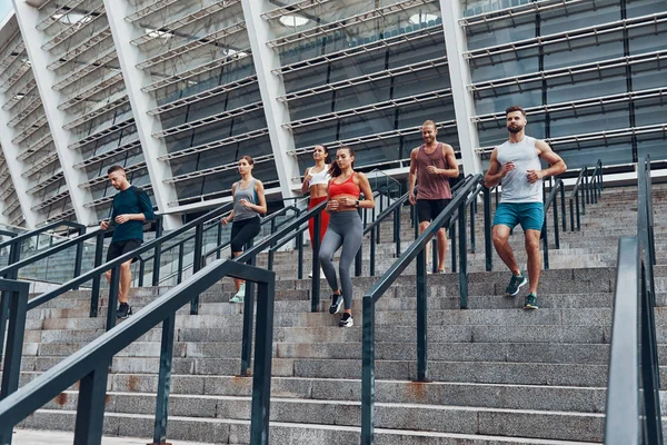 一群运动人士在城市楼梯上慢跑 在奥林匹克体育场的背景 — 图库照片