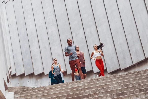 Grupo Deportistas Trotando Ciudad Las Escaleras Gran Pared Hormigón — Foto de Stock