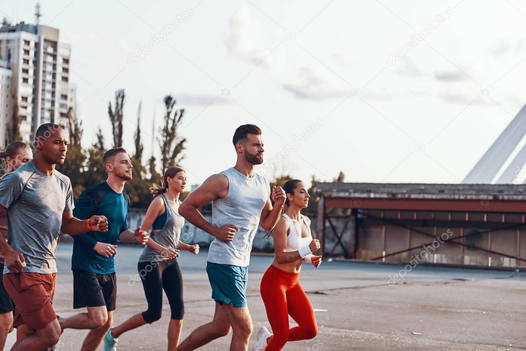 strong, sportive people in sports clothing running in city 