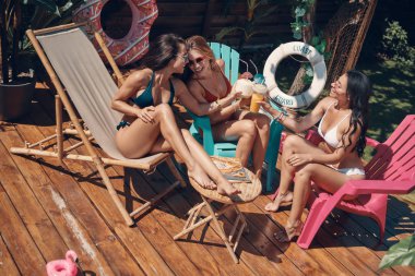 Tropik tatil de rahatlatıcı ve hindistan cevizi kokteylleri olan mayo çekici genç kadınlar
