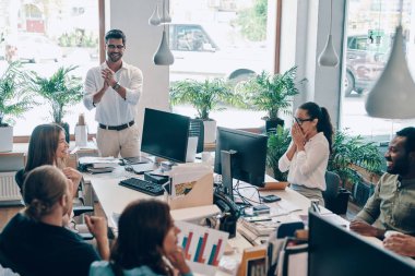 Akıllı gündelik giyimde genç modern bir grup, ofiste çalışırken modern teknolojileri kullanarak iletişim kuruyor ve kullanıyor  