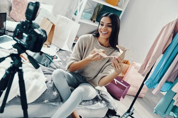 Beautiful young woman in casual clothing making social media video and showing shoe