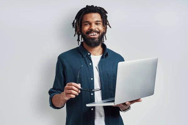 Encantador Jovem Africano Óculos Usando Laptop Enquanto Está Contra Fundo — Fotografia de Stock