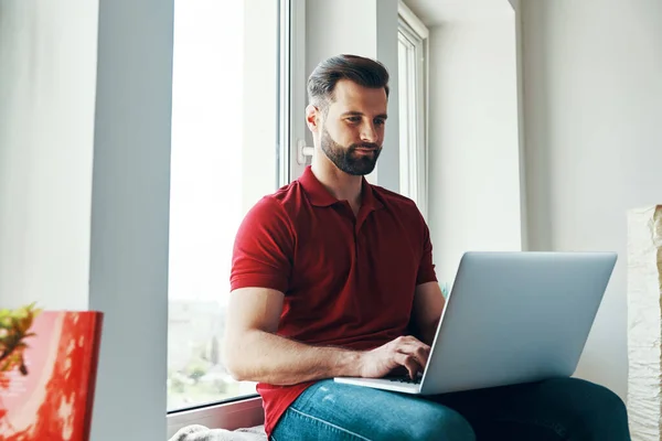 Encantador Joven Con Ropa Casual Usando Ordenador Portátil Mientras Está — Foto de Stock