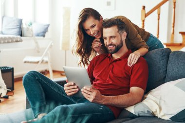 Gündelik giysiler içinde genç ve güzel bir çift kanepede dinlenirken birbirlerine bağlanıp gülüyorlar.