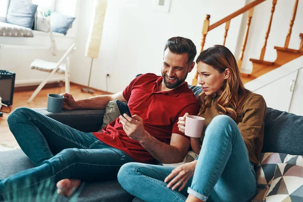 Feliz Pareja Joven Ropa Casual Uniéndose Sonriendo Mientras Descansan Sofá —  Fotos de Stock