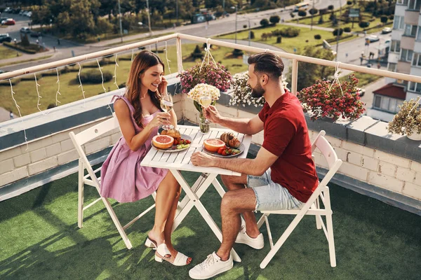 屋上のパティオ屋外に座っている間 ロマンチックなディナーと笑顔を楽しむカジュアルな服で屈託のない若いカップルのトップビュー — ストック写真