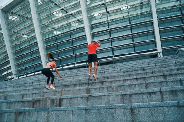 Spor elbiseli genç bir çift açık havada spor yapıyor.