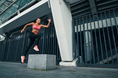 Açık havada egzersiz yaparken havada süzülen spor elbiseli çekici bir kadın.