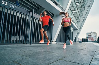 Spor elbiseli iki genç sporcunun açık havada koşması tam boy.