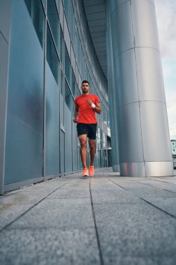 Spor kıyafetleriyle koşan, dışarıda egzersiz yapan sıska bir genç.