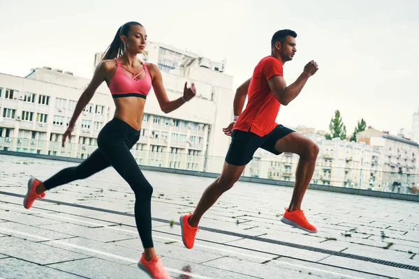 自信に満ちた若い男性と女性のスポーツウェアで屋外でジョギング — ストック写真