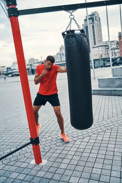 Longitud Completa Joven Confiado Ropa Deportiva Pateando Saco Boxeo Mientras — Foto de Stock