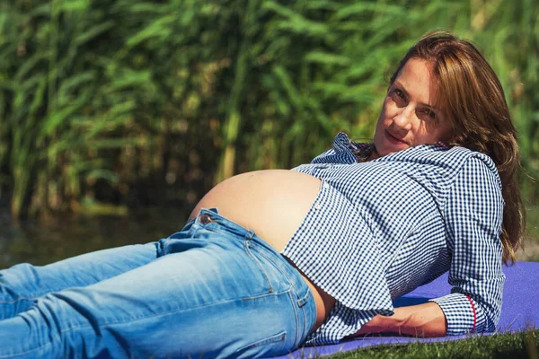 草の上に横たわる太陽の下で腹を持つ妊婦 — ストック写真