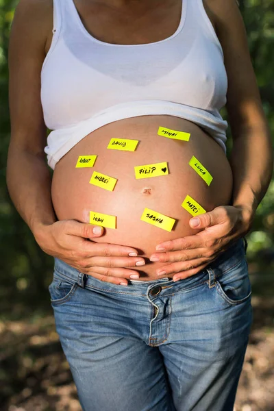 怀孕妇女触摸腹部 并贴有婴儿名的贴纸 — 图库照片