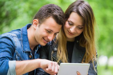 Güzel kız arkadaşına dijital tablet hakkında bilgi veren gülümseyen bir adamın yakın çekimi. 