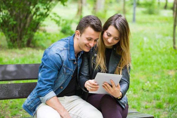 Park bankında dijital tablet kullanan genç çift