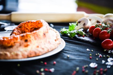 Lezzetli İtalyan calzone pizza yemeği ve taze malzemeler.