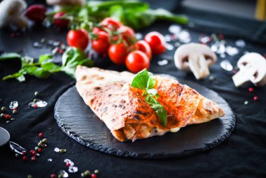 Lezzetli İtalyan calzone pizza yemeği ve taze malzemeler.